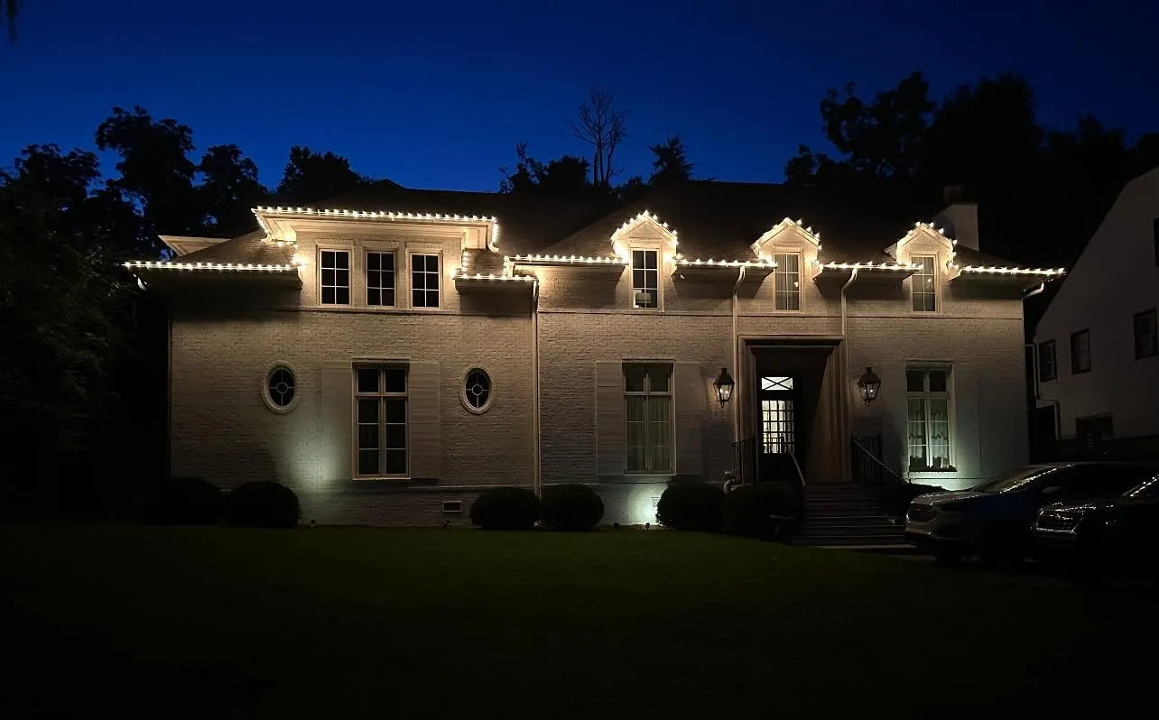 Home with warm white roofline Christmas lighting at night in the Birmingham, Alabama area